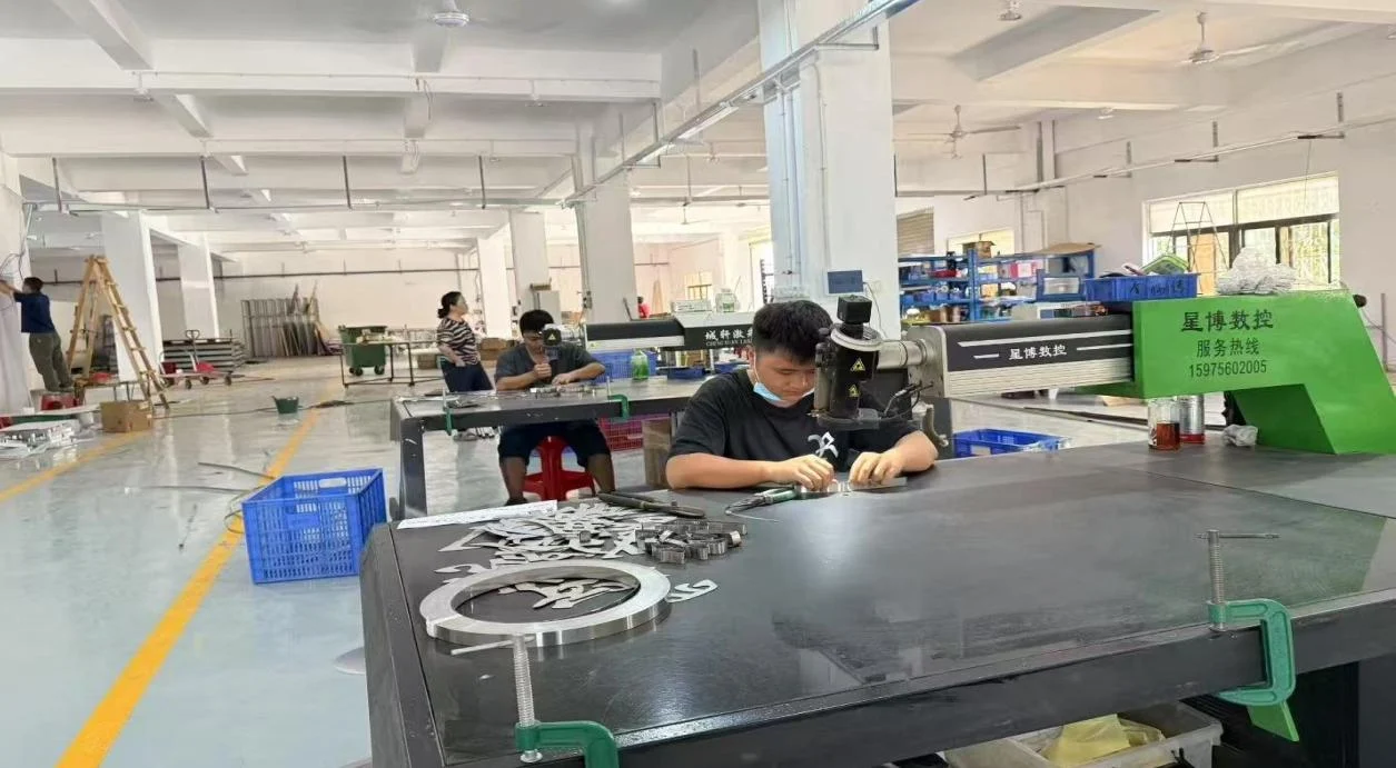Skilled fabricators working on custom metal lettering in the workshop